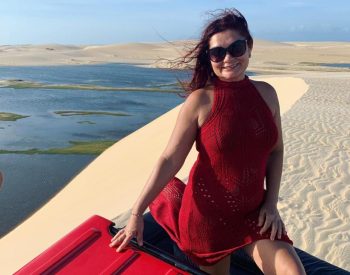 Mulher tirando foto em cima do buggy com dunas e lagoa atrás